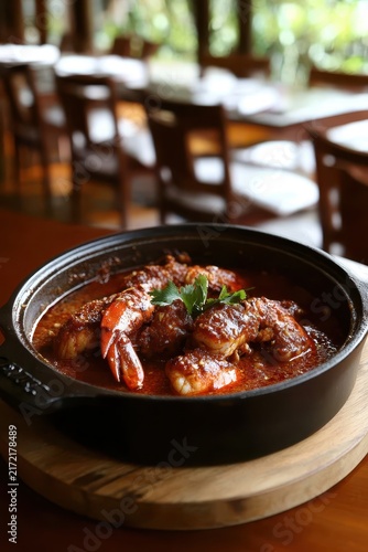 Delicious seafood stew in a black clay pot served with herbs