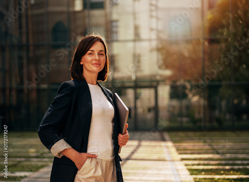 Businesswoman standing with a laptop outside a modern office
