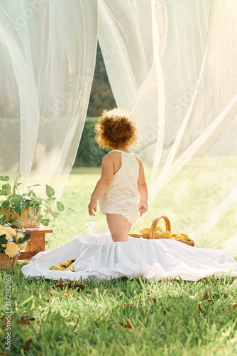     Adorable toddler girl in white outfit playing with fresh lemons