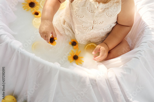     Toddler girl enjoying a lemon bath outdoors in a sunny garden
