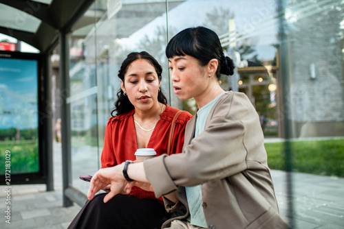 Two women checking time at urban bus stop