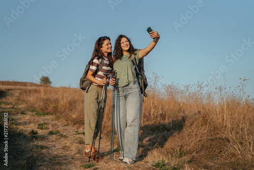 Women friends hiking taking selfie on trail