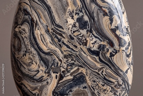 Picasso jasper metamorphic rock macro with abstract marbled art-like patterns on solid warm grey background