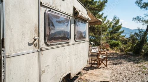 Old vintage caravan trailer parked at forest campsite. Retro camper van for summer road trip and outdoor camping vacation. Nomad lifestyle and travel adventure concept.
