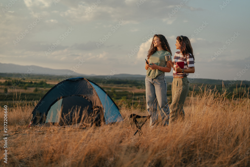 Obraz premium Friends camping outdoors at sunset enjoying nature