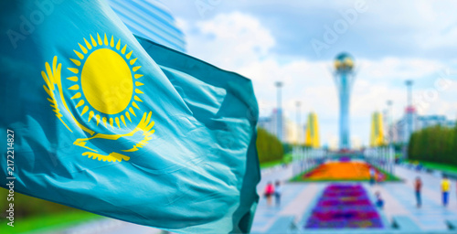 Obraz na płótnie The flag of the Republic of Kazakhstan waves in the wind, with an avenue in the capital city of Astana in the background