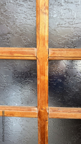 Wooden window frame with cross bars over dark background