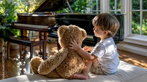 Cute boy sits with teddy bear by the piano