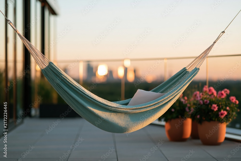 Naklejka premium Green hammock with pillow on balcony terrace at golden hour for urban relaxation background and lifestyle banner