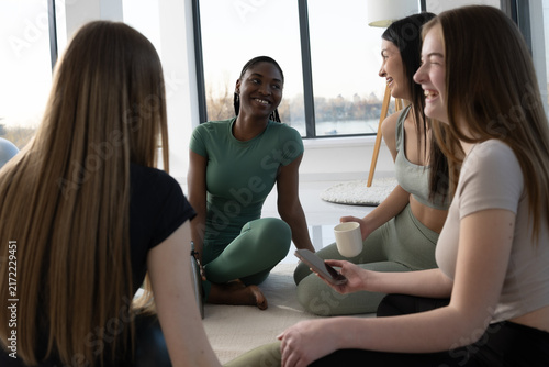 Diverse group of women in activewear chatting and laughing after a workout session