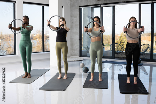 Four women in activewear performing pilates exercises with fitness rings