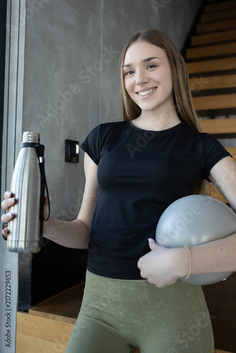 Young woman with fitness ball and water bottle ready for a workout session