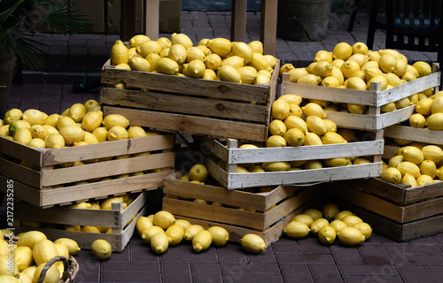 Fresh yellow lemons piled in rustic wooden crates at an outdoor market, creating a vibrant display of Mediterranean produce.