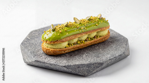 An eclair dessert with pistachios on a white background