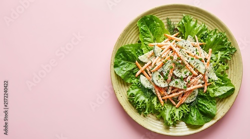 Fresh healthy salad with shredded carrots and green lettuce leaves served on a round plate