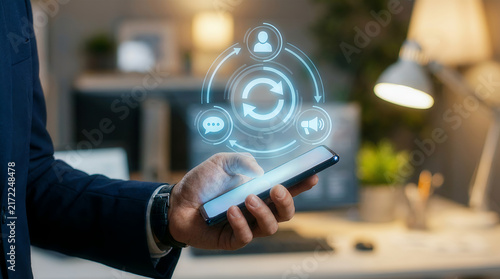 Businessman holding smartphone with digital communication icons