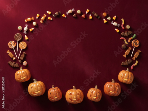 Halloween pumpkin and candy wreath border on dark red background