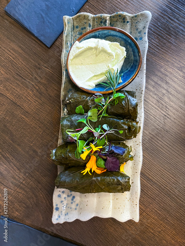Dolma - Traditional Dish of Georgian Cuisine - Stuffed Grape Leaves with Meat served with Sauce Decorated with Flowers on a Plate. Top View.