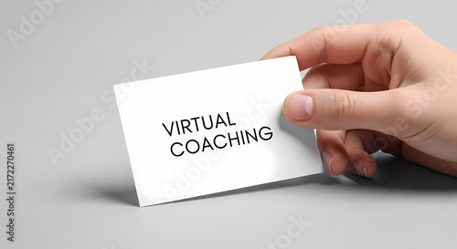 Virtual coaching card held by hand against minimalist grey background with sharp focus for professional mentorship marketing
