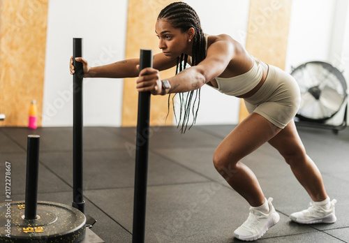 Fotografía Woman pushing heavy weighted sled during intense gym workout