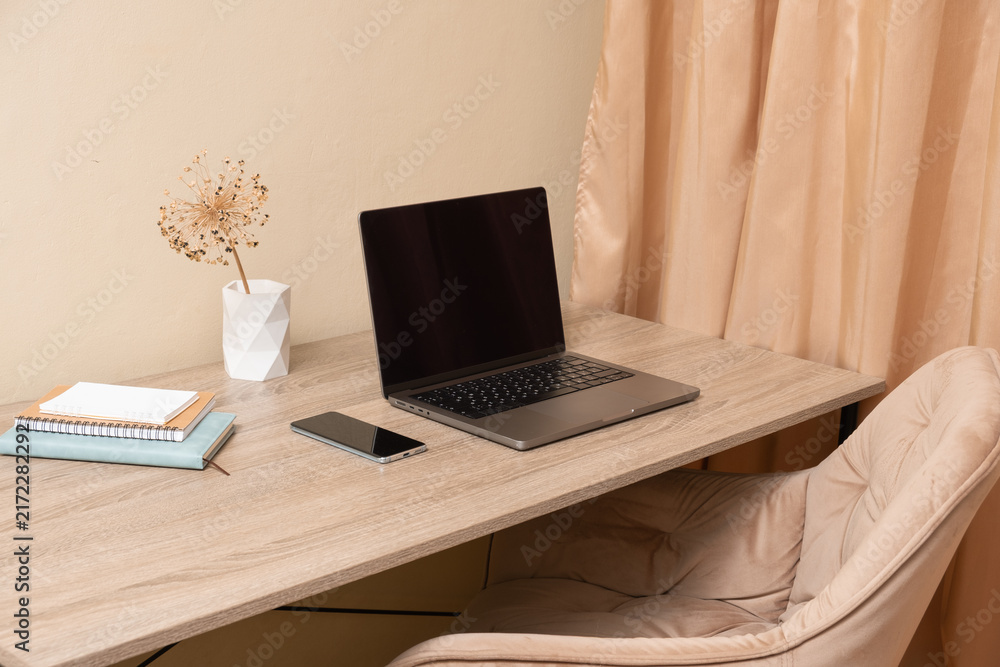 Fototapeta premium Desk with a laptop, phone, and plant in a simple indoor workspace