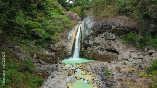 Aerial pullback from Mangku Sakti waterfall revealing turquoise river and jungle gorge Lombok