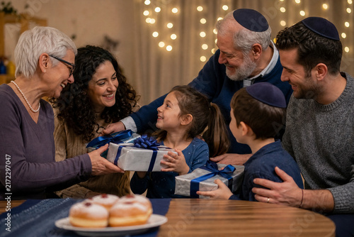 A Joyful Jewish Family Celebration: A multi-generational Jewish family gathers around a table, sharing gifts and laughter during a festive occasion.