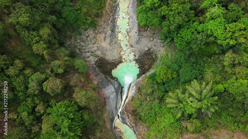 High top down aerial view of Mangku Sakti waterfall and turquoise stream in jungle canyon Lombok