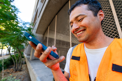 man in orange safety vest using mobile phone speakerphone call