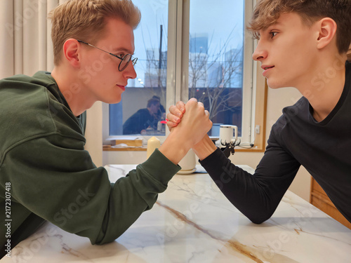 Canvastavla Two young men arm-wrestling at a marble countertop