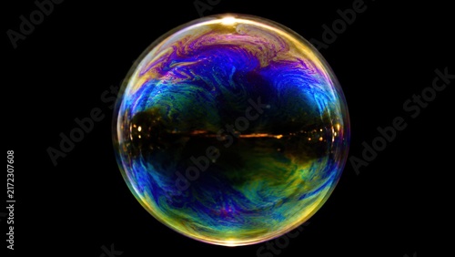 Macro iridescent soap bubble floating on black background
