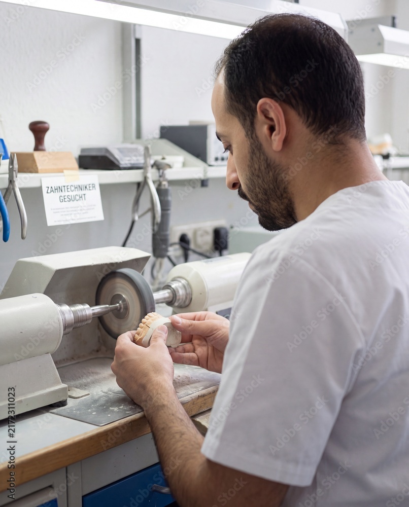 Fototapeta premium Zahntechniker gesucht Mann poliert Zahnersatz im Dentallabor