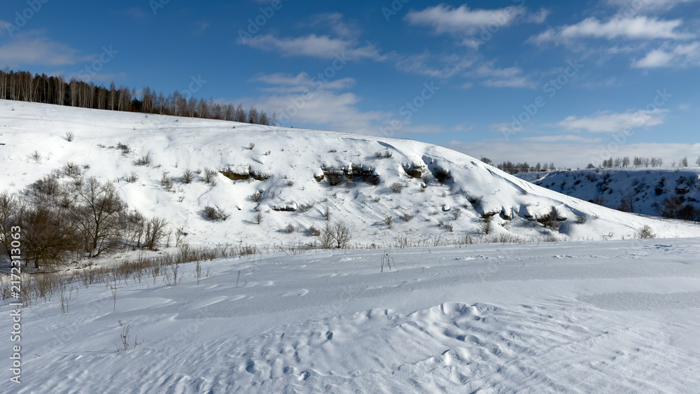Fototapeta premium Snow blankets rolling hills under bright blue sky