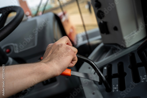 Close up of driver hand shifting gear lever on control console inside modern agricultural tractor cabin during machinery operation.