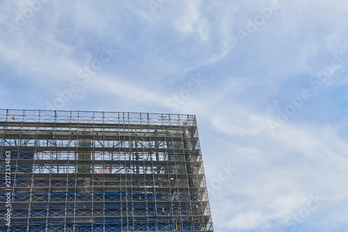 Plakat 青空のもと足場と養生シートに覆われて建設が進む高層ビルの外観