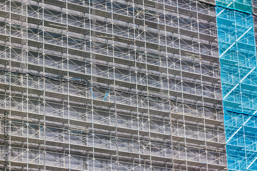 Obraz na płótnie 建設中のビルに規則正しく組まれた足場と鉄骨が作り出す幾何学模様
