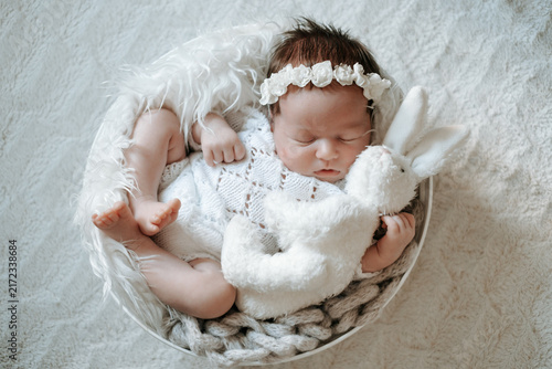 A newborn baby is sleeping in the crib; there's room for text. The little baby is sleeping sweetly.