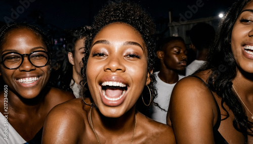 Young woman laughing at an outdoor night event surrounded by a crowd of people.