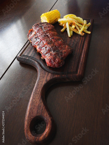 Fotografie costillas bbq a la parrilla en tabla de parota, con elote y papas a la francesa