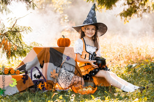 фотографія Girl Celebrates Halloween in Autumn With a Pumpkin and Spiderweb in a Park on a