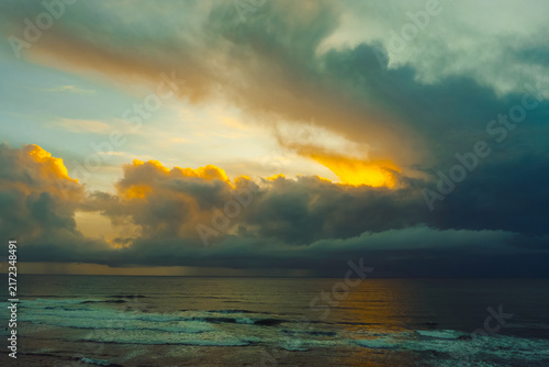 Bild auf Leinwand Clouds fill the sky over the ocean as the sun sets in the evening