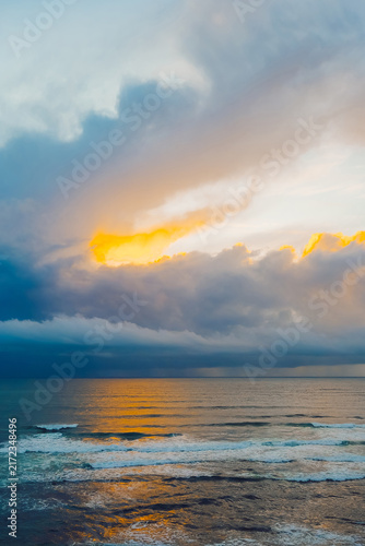Bild auf Leinwand Clouds fill the sky over the ocean as the sun sets in the evening
