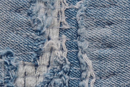 Extreme macro shot of torn denim fabric displaying frayed threads and woven cotton texture.