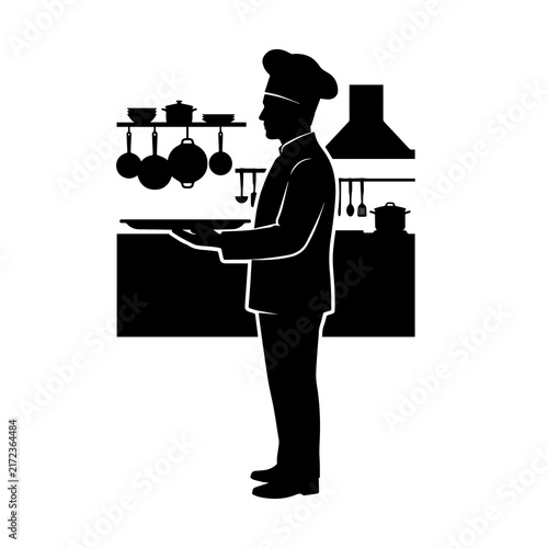 Chef silhouette holding a tray in a restaurant kitchen with cooking staff