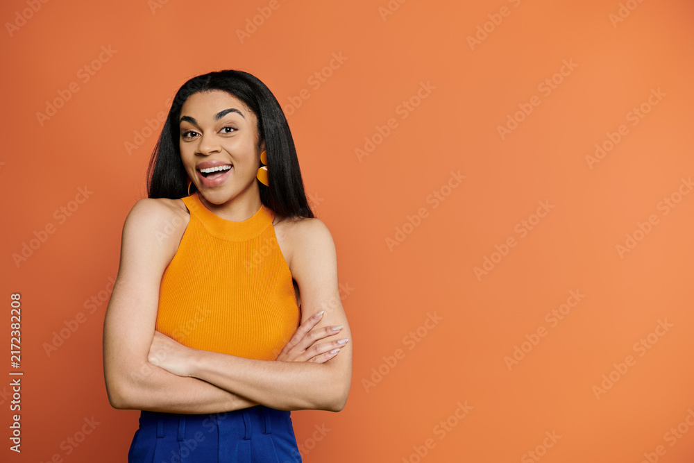 Obraz premium Beautiful African American woman smiles joyfully against a vibrant orange backdrop