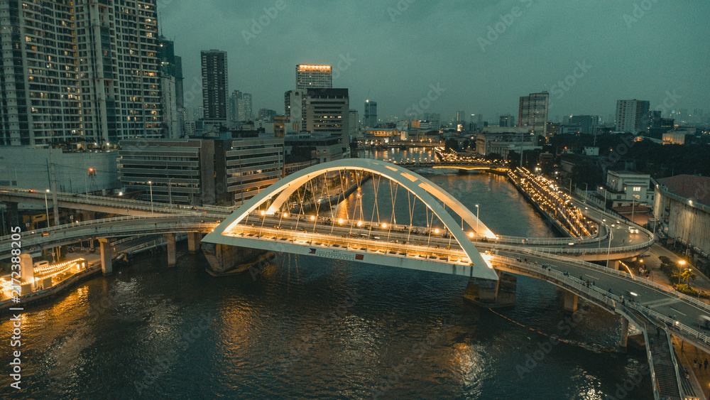 Fototapeta premium Illuminated Binondo Intramuros Bridge aerial view over Pasig River and Manila cityscape at night, Philippines