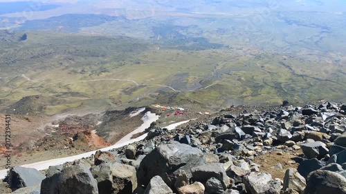 High camp on Mount Ararat seen in wide view from higher altitude, with rocky volcanic slopes and snowfields below, showing expedition scale, route elevation, summit approach, and mountain logistics