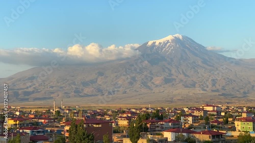 Mount Ararat rising in wide view above Dogubayazit at sunrise in eastern Turkey, showing snow covered summit, urban foreground, volcanic landscape, regional tourism, destination branding, and travel