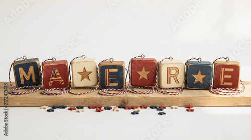 Primitive fabric letter blocks with star accents on wooden shelf with scattered berries isolated on white background, farmhouse rustic decor for patriotic Americana home decoration concept design