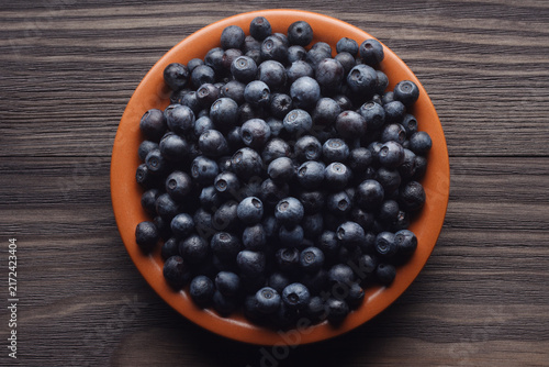 Clay plate of fresh blueberries on wooden table